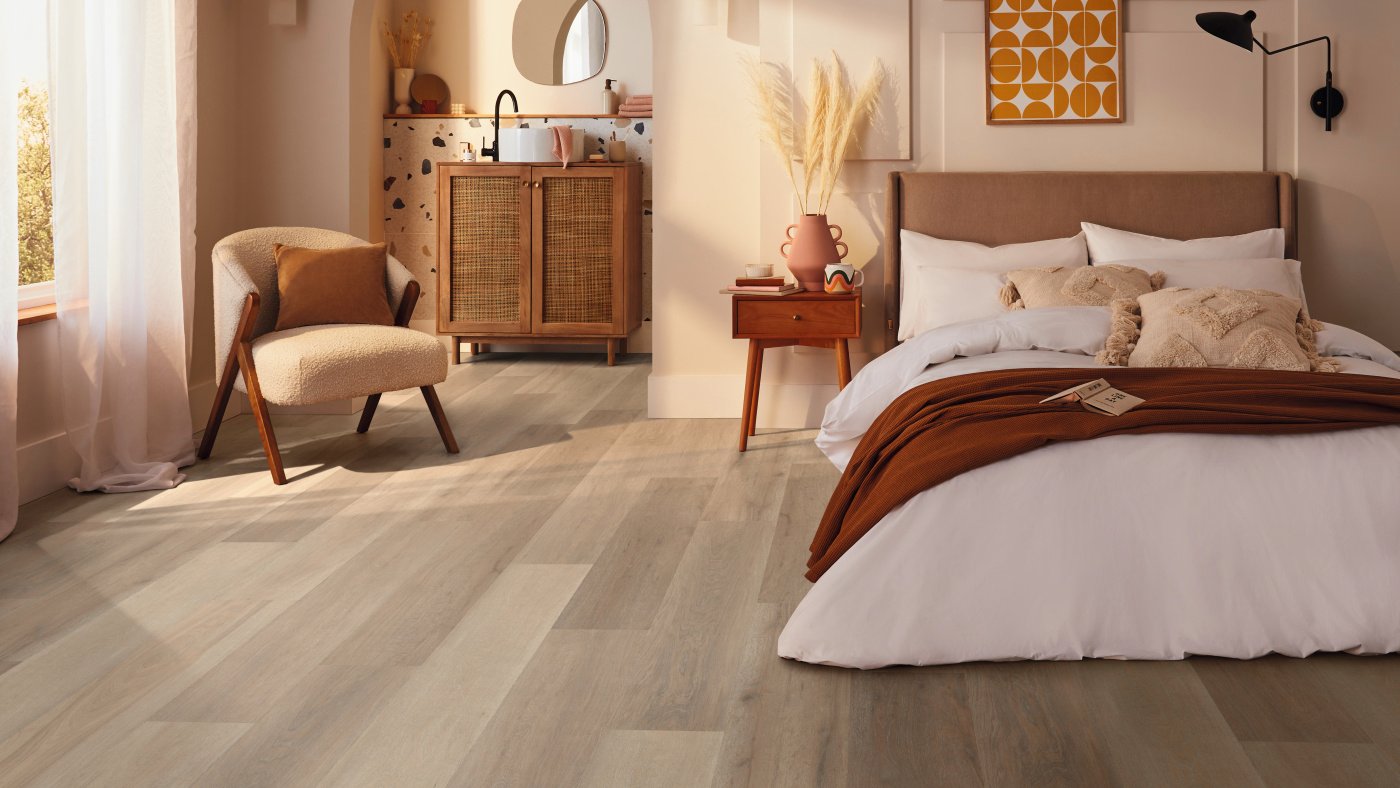 Light brown plank flooring in a modern bedroom with chair.