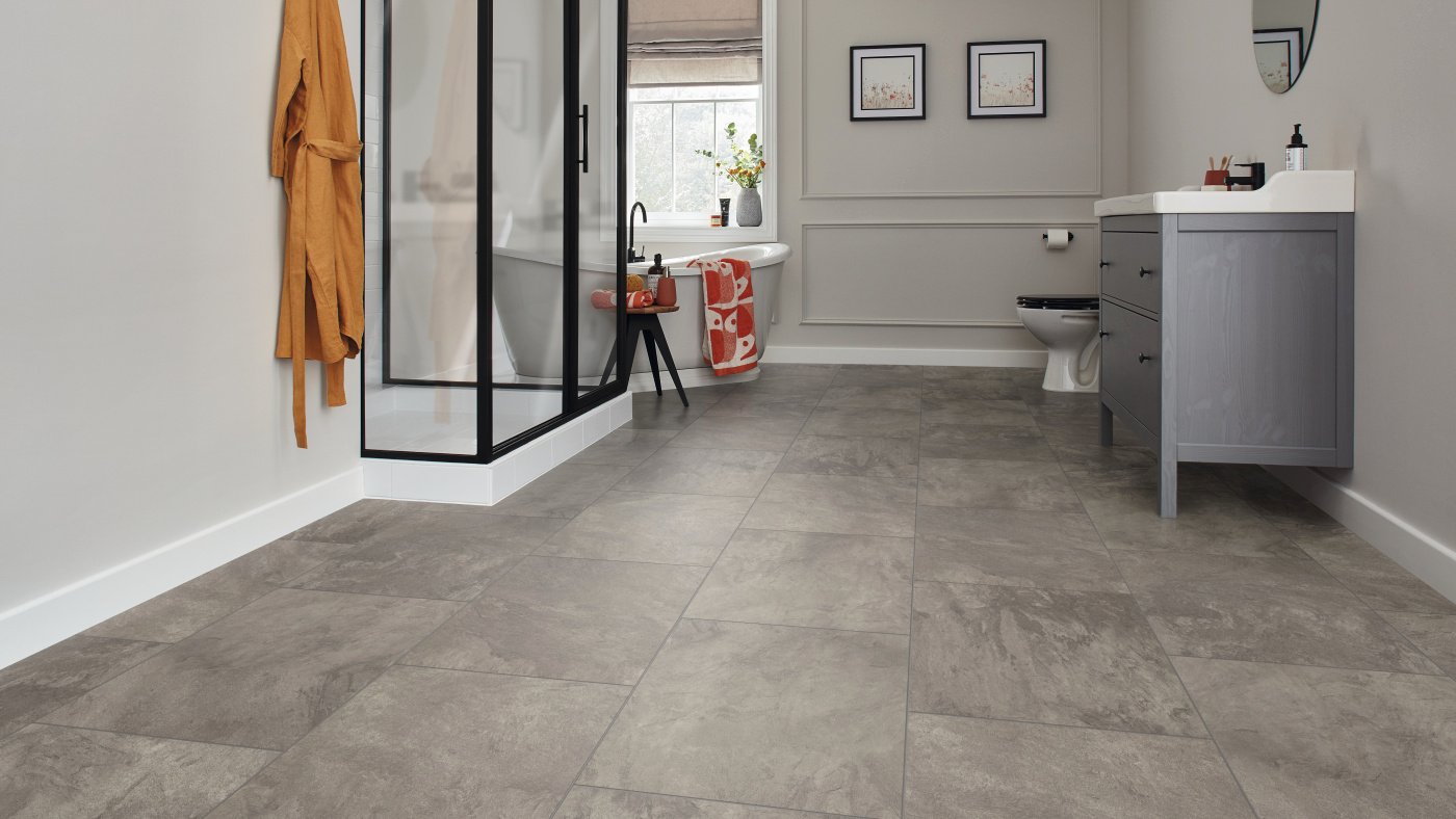 Brown stone flooring in an specious bathroom with a walk in shower.