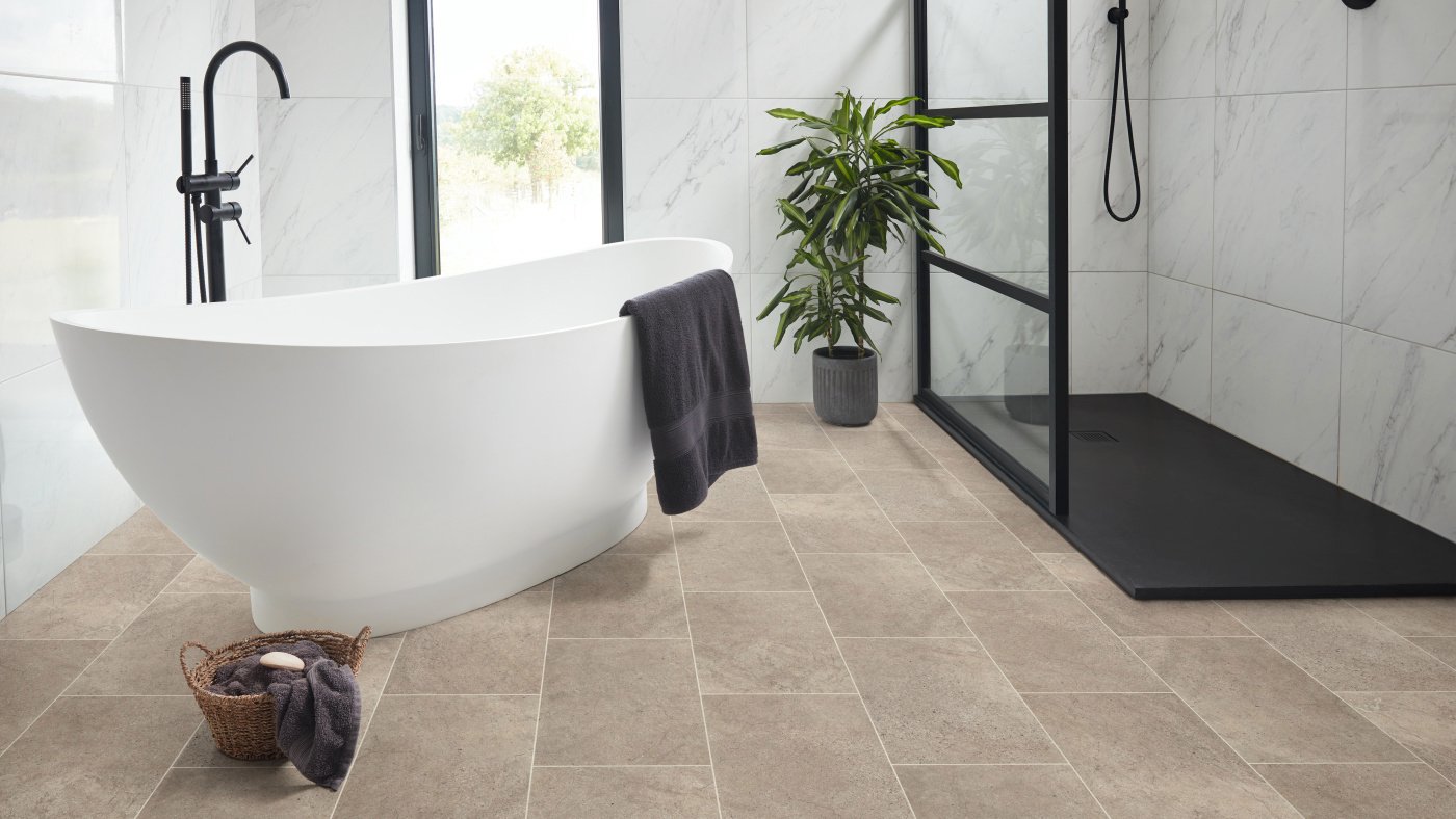 Begie stone flooring in a bathroom with free standing bath and shower cubical. 