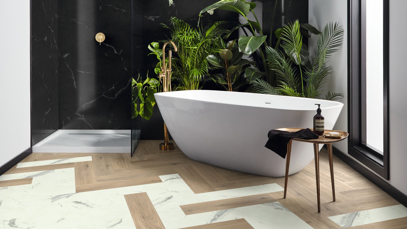 Brown and white herrinbone flooring in a bathroom with a standalone white bath and walk in shower.